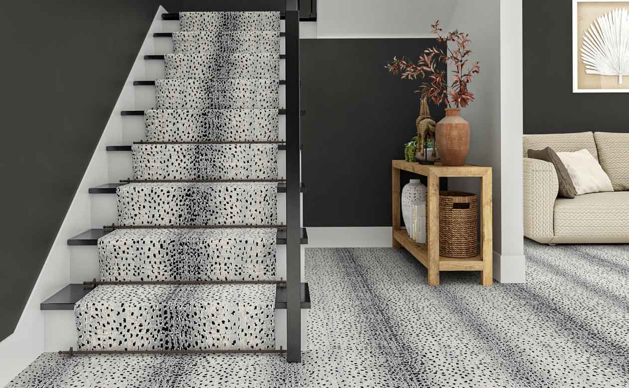 animal print gray carpet in entryway with carpeted staircase, dark gray walls and styled entryway table