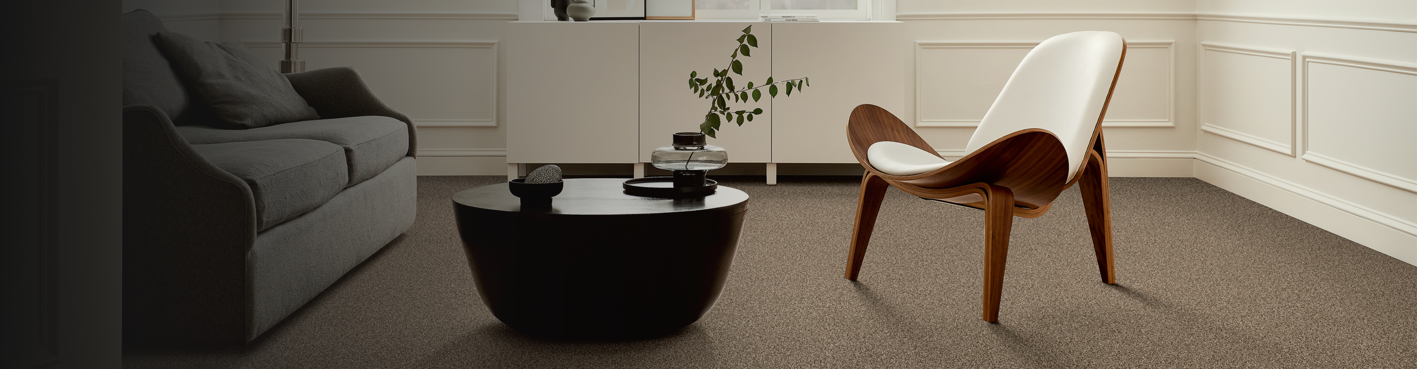 mid century modern living room with gray couch, white chair, black coffee table, and beige carpet